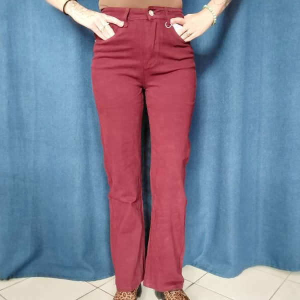 Vu de face jeans bordeaux, taille haute coupe droite légèrement évasée sur le bas.Bouton et zip pour la fermeture.