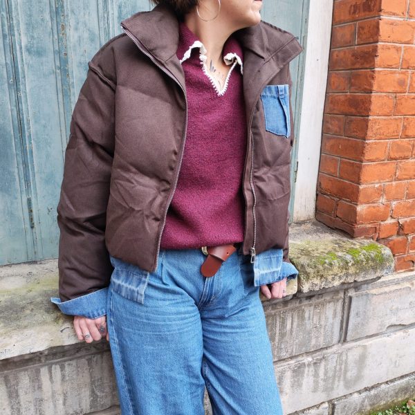 Doudoune marron à détails en jean, poche en jean sur le torse, finition en jean sur les poignets, et sur le bas de la doudoune.