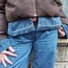 Doudoune marron à détails en jean, poche en jean sur le torse, finition en jean sur les poignets, et sur le bas de la doudoune.