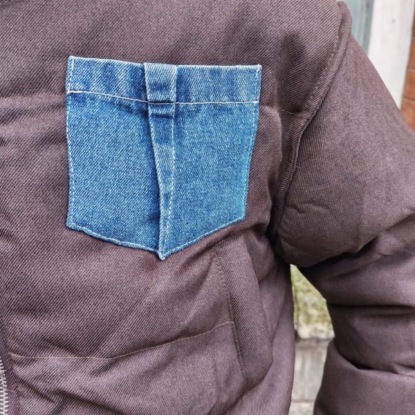Doudoune marron à détails en jean, poche en jean sur le torse, finition en jean sur les poignets, et sur le bas de la doudoune.