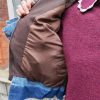 Doudoune marron à détails en jean, poche en jean sur le torse, finition en jean sur les poignets, et sur le bas de la doudoune.