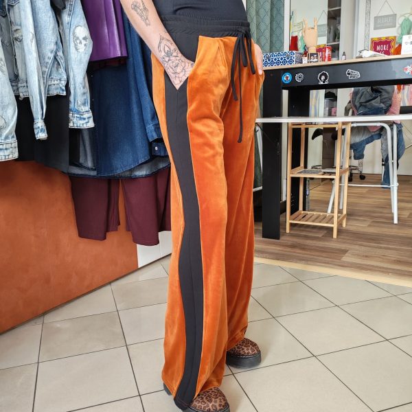 Pantalon velours orange vif avec ligne noir intense sur les côtés. 2 poches pratiques.
