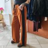 Pantalon velours orange vif avec ligne noir intense sur les côtés. 2 poches pratiques.