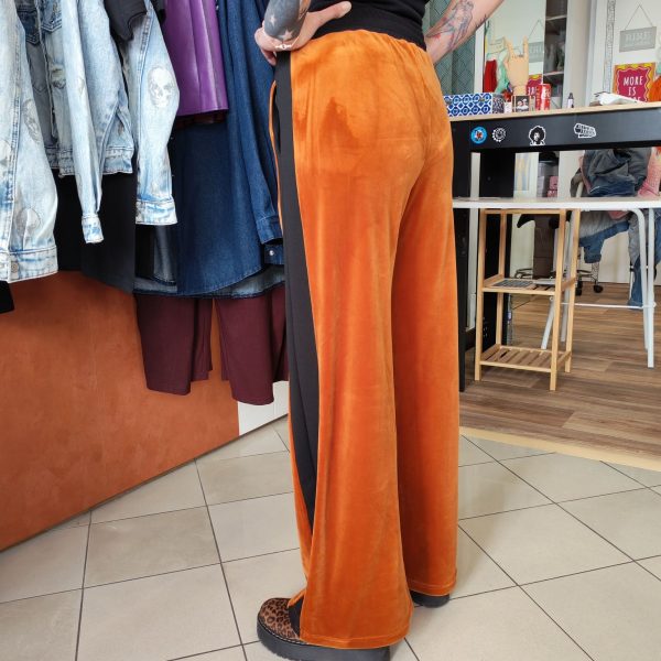 Pantalon velours orange vif avec ligne noir intense sur les côtés. 2 poches pratiques.
