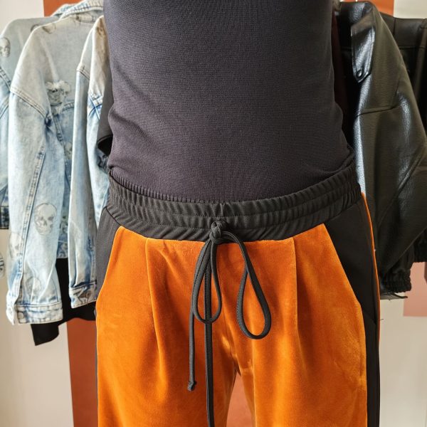 Pantalon velours orange vif avec ligne noir intense sur les côtés. 2 poches pratiques.