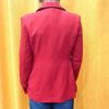 Blazer rouge épaules légèrement marquées. Motifs broderies noires (œil, cœur sacré, rouge à lèvres, diamant, revolver, rose, inscription " Ex-Wives Club). Tissu lisse et confortable, double rangée de boutons noires pour la fermeture, coupe ajustée.