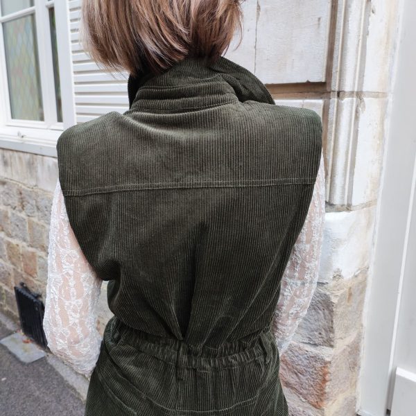 Combinaison longue sans manches Robes / Combinaisons / Salopettes Mademoiselle Hélène Combinaison longue sans manches en velours côtelé vert. Coupe longue, col chemise structuré, fermeture boutonnée sur le devant, poches poitrine et poches latérales, taille marquée pour une silhouette féminine.
