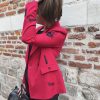 Blazer rouge épaules légèrement marquées. Motifs broderies noires (œil, cœur sacré, rouge à lèvres, diamant, revolver, rose, inscription " Ex-Wives Club). Tissu lisse et confortable, double rangée de boutons noires pour la fermeture, coupe ajustée.