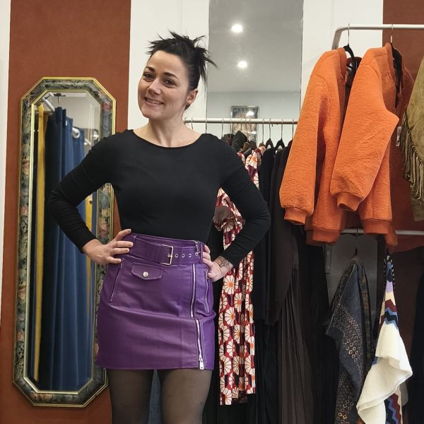 Jupe courte violette en simili cuir zippée, taille haute, fermeture zippée sur le devant, ceinture intégrée avec œillets métalliques, poches décoratives à l'avant et à l'arrière, coupe structurée et confortable