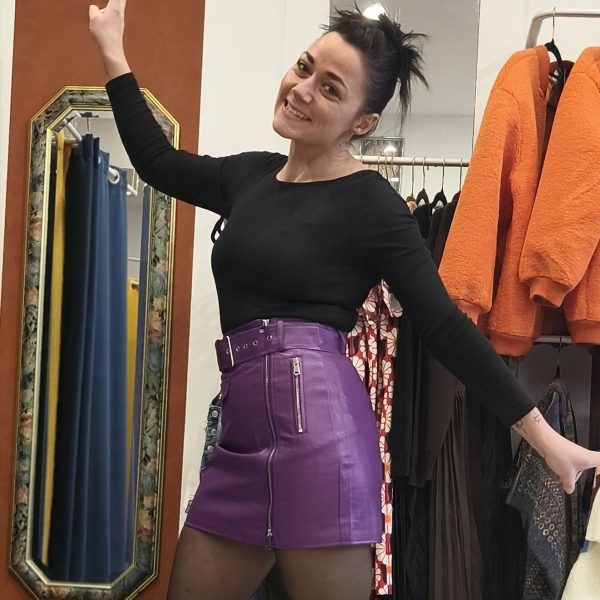 Jupe courte violette en simili cuir zippée, taille haute, fermeture zippée sur le devant, ceinture intégrée avec œillets métalliques, poches décoratives à l'avant et à l'arrière, coupe structurée et confortable
