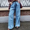 Jeans large taille haute denim bleu clair fermeture avec une patte de boutonnage croisé qui crée un effet asymétrique à la taille.