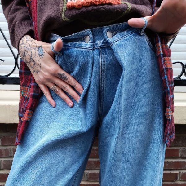 Jeans large taille haute denim bleu clair fermeture avec une patte de boutonnage croisé qui crée un effet asymétrique à la taille.
