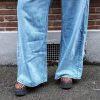 Jeans large taille haute denim bleu clair fermeture avec une patte de boutonnage croisé qui crée un effet asymétrique à la taille.