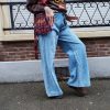 Jeans large taille haute denim bleu clair fermeture avec une patte de boutonnage croisé qui crée un effet asymétrique à la taille.