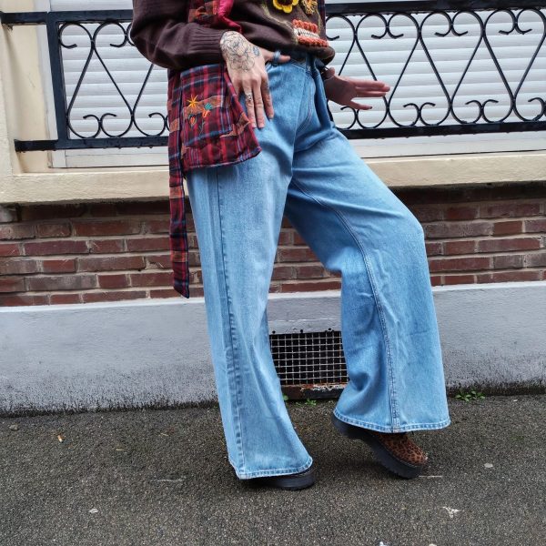 Jeans large taille haute denim bleu clair fermeture avec une patte de boutonnage croisé qui crée un effet asymétrique à la taille.