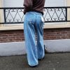 Jeans large taille haute denim bleu clair fermeture avec une patte de boutonnage croisé qui crée un effet asymétrique à la taille.
