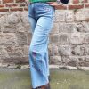 Jean barrel brodé love Jeans Mademoiselle Hélène Jean barrel brodé love, taille haute, denim clair délavé, broderies cœurs, fleurs et inscription, fermeture bouton + zip, longueur cheville / pleine longueur selon taille.