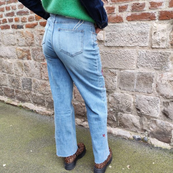 Jean barrel brodé love Jeans Mademoiselle Hélène Jean barrel brodé love, taille haute, denim clair délavé, broderies cœurs, fleurs et inscription, fermeture bouton + zip, longueur cheville / pleine longueur selon taille.