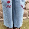 Jean barrel brodé love Jeans Mademoiselle Hélène Jean barrel brodé love, taille haute, denim clair délavé, broderies cœurs, fleurs et inscription, fermeture bouton + zip, longueur cheville / pleine longueur selon taille.
