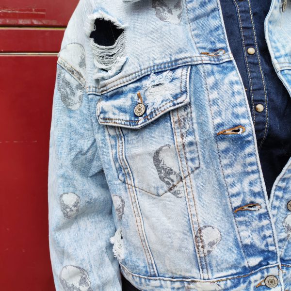 Veste en jean skull délavé, imprimé crânes, effet destroy avec détails usés, fermeture par boutons, poches poitrine avec rabat, coupe moderne et confortable, style rock.