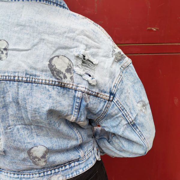 Veste en jean skull délavé, imprimé crânes, effet destroy avec détails usés, fermeture par boutons, poches poitrine avec rabat, coupe moderne et confortable, style rock.