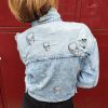 Veste en jean skull délavé, imprimé crânes, effet destroy avec détails usés, fermeture par boutons, poches poitrine avec rabat, coupe moderne et confortable, style rock.