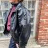 Veste simili cuir noire structurée, effet cuir texturé, coupe oversize, col montant avec boutons, fermeture zip frontal avec rabat asymétrique. Taille unique