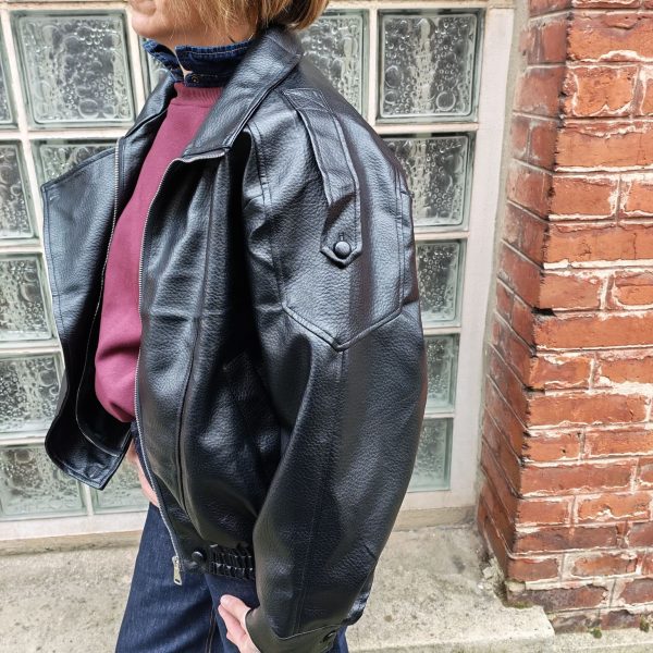 Veste simili cuir noire structurée, effet cuir texturé, coupe oversize, col montant avec boutons, fermeture zip frontal avec rabat asymétrique. Taille unique