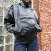 Veste simili cuir noire structurée, effet cuir texturé, coupe oversize, col montant avec boutons, fermeture zip frontal avec rabat asymétrique. Taille unique