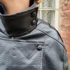 Veste simili cuir noire structurée, effet cuir texturé, coupe oversize, col montant avec boutons, fermeture zip frontal avec rabat asymétrique. Taille unique