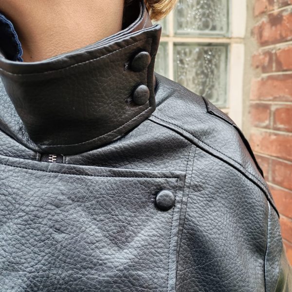 Veste simili cuir noire structurée, effet cuir texturé, coupe oversize, col montant avec boutons, fermeture zip frontal avec rabat asymétrique. Taille unique