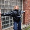 Veste simili cuir noire structurée, effet cuir texturé, coupe oversize, col montant avec boutons, fermeture zip frontal avec rabat asymétrique. Taille unique