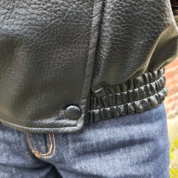 Veste simili cuir noire structurée, effet cuir texturé, coupe oversize, col montant avec boutons, fermeture zip frontal avec rabat asymétrique. Taille unique