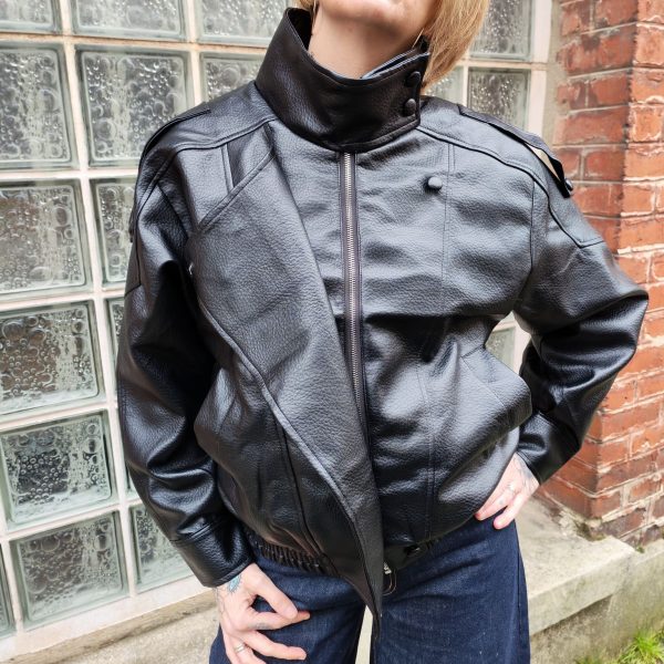 Veste simili cuir noire structurée, effet cuir texturé, coupe oversize, col montant avec boutons, fermeture zip frontal avec rabat asymétrique. Taille unique