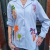 Chemise rayée brodée tropical Dernières Chances Mademoiselle Hélène Chemise rayée brodée tropicale, rayures verticales, broderies multicolores motif tropical, coupe confortable, légèrement ample, fermeture boutonnée sur le devant, col chemise classique, manches longues avec poignets boutonnés, matière légère et agréable à porter.