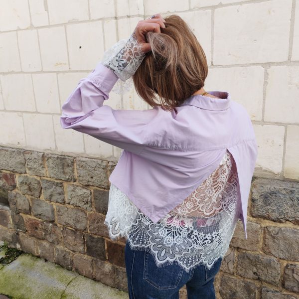 Chemise courte dentelle lilas, courte et légèrement ample, manches longues finitions dentelle, fermeture boutonnée sur le devant.