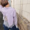 Chemise courte dentelle lilas, courte et légèrement ample, manches longues finitions dentelle, fermeture boutonnée sur le devant.