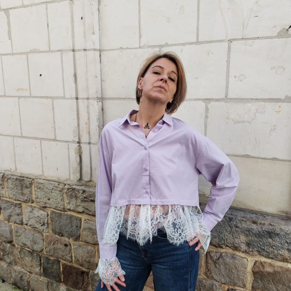 Chemise courte dentelle lilas, courte et légèrement ample, manches longues finitions dentelle, fermeture boutonnée sur le devant.