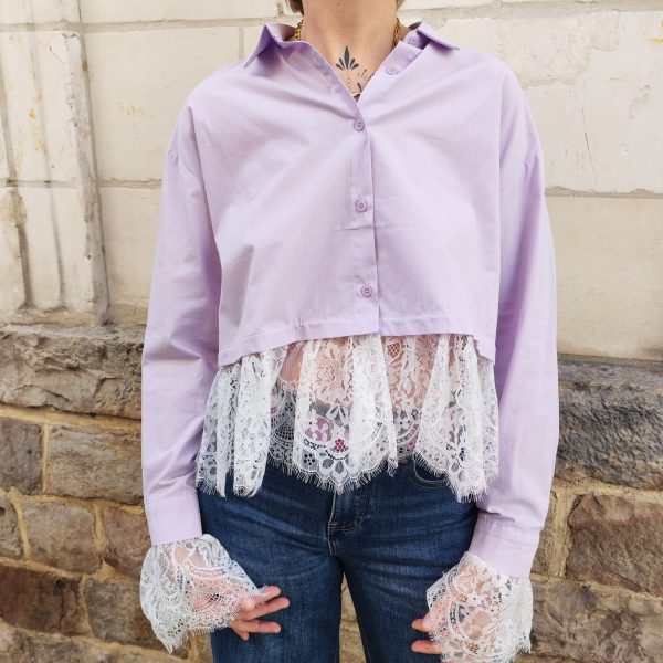 Chemise courte dentelle lilas, courte et légèrement ample, manches longues finitions dentelle, fermeture boutonnée sur le devant.