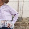 Chemise courte dentelle lilas, courte et légèrement ample, manches longues finitions dentelle, fermeture boutonnée sur le devant.