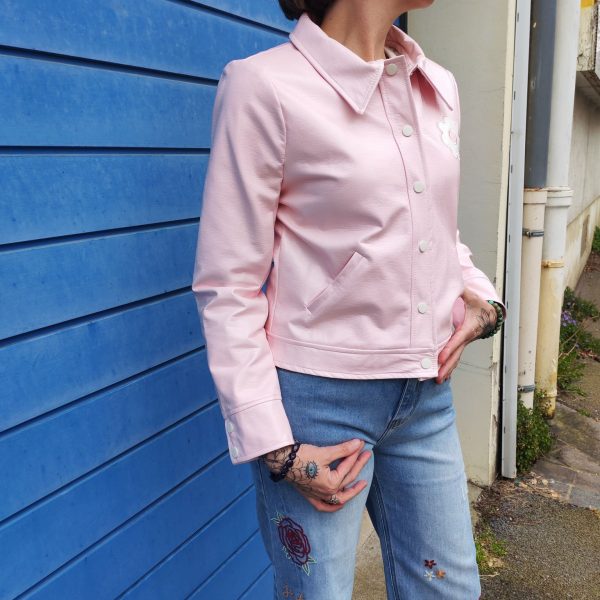 Veste rose vinyle Hippocampe, coupe droite légèrement ajustée, boutons pression, col chemise structuré, manches longues, patch fleur brodé sur la poitrine, deux poches latérales; Disponible du 36 au 44.
